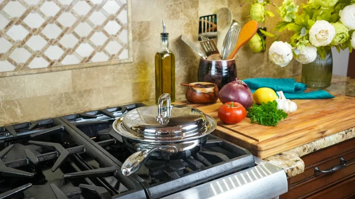 Angled view of 1.5 qt stainless-steel saute pan with lid and long handle on gas stove, cutting board and vegetables in background