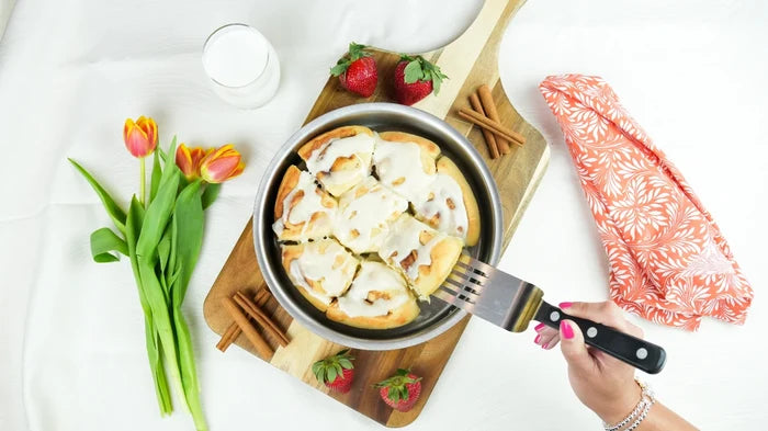 Top-down view of 9-inch round cake pan (no handles) showing stainless-steel interior and rolled rim on wooden cutting board