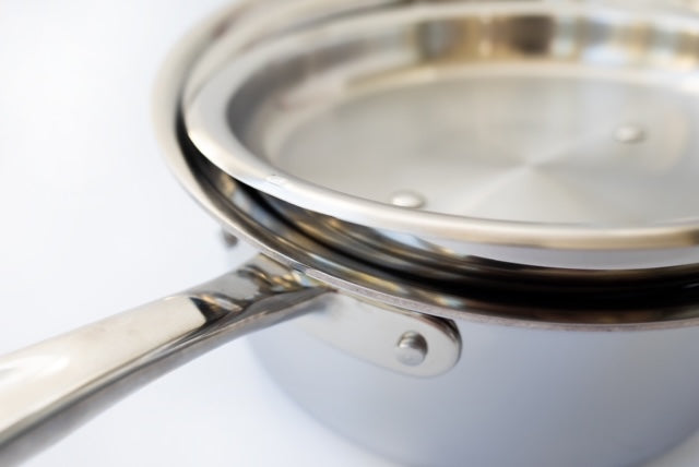 Stainless-steel saucepan with lid slightly ajar, long handle and visible rivets
