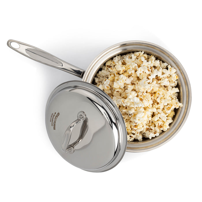 Stainless-steel saucepan filled with popped popcorn with lid partially open.