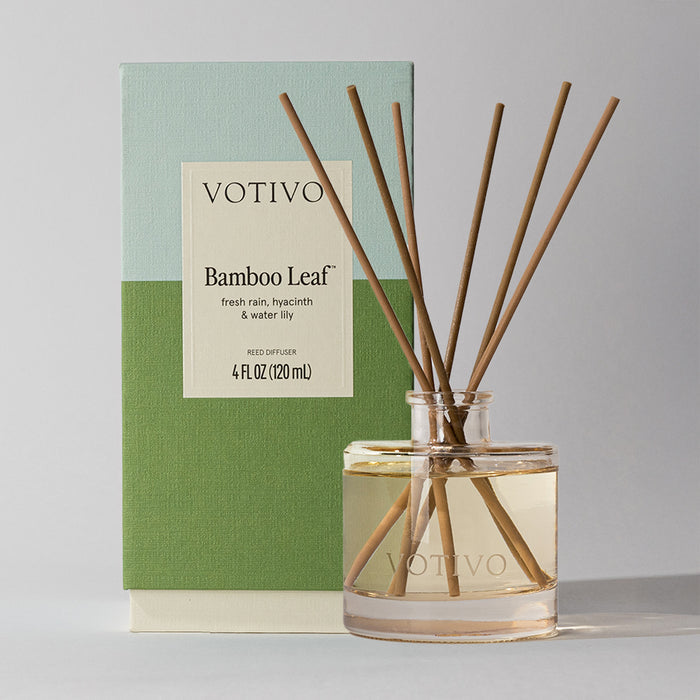 The Votivo Bamboo Leaf Reed Diffuser features fiber reeds in a glass bottle, presented with its green and blue box showing the scent name and 4 fl oz (120 ml) size.