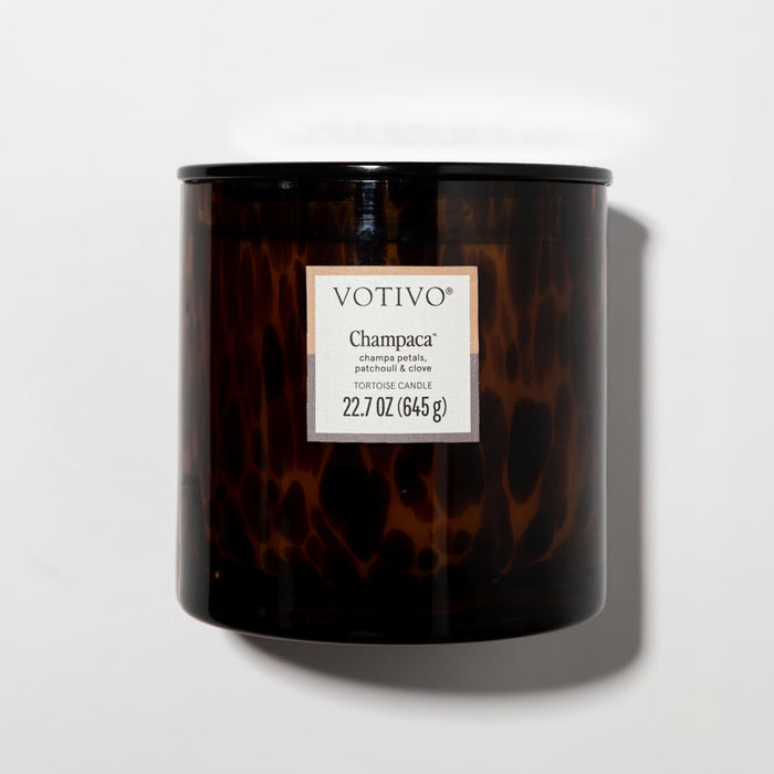 A brown speckled tortoiseshell vessel Votivo Champaca Tortoise Candle, 22.7 oz (645g), soy blend wax, with scents of champa petals, patchouli & clove, displayed against a plain white background.