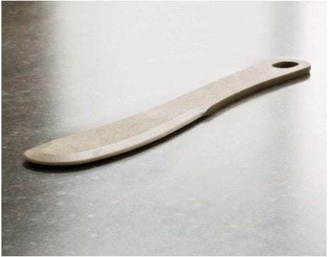 Side view of Cheese Spreader showcasing curved spreading blade and hanging hole on a gray countertop