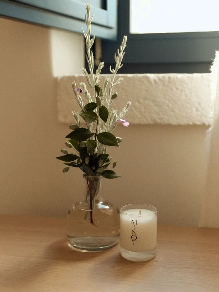 Cerulean Tide Mini soy candle emanates coastal minimalism next to a small bouquet of soft greenery