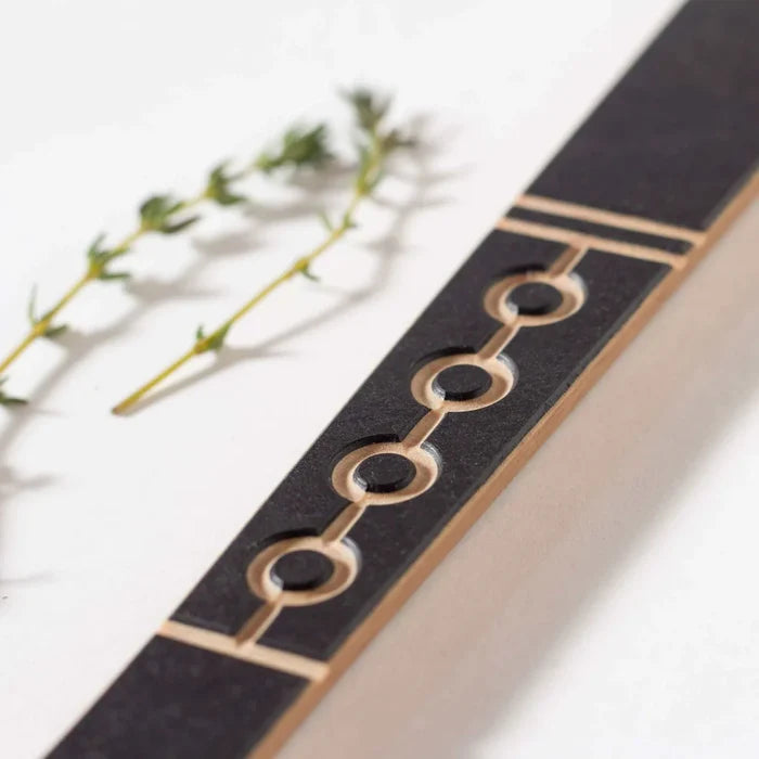 Close-up of Frank Lloyd Wright Paddle showcasing circular cutouts and layered wood inlay on white background