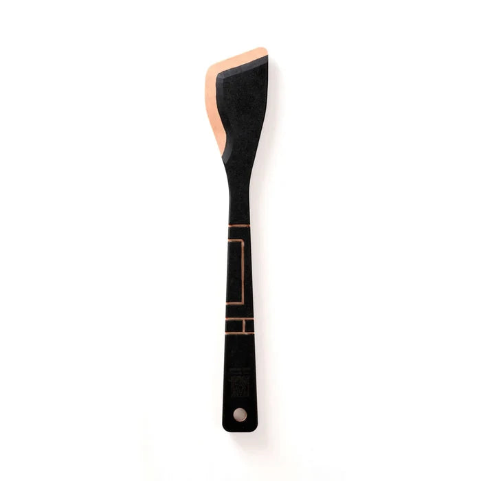 Front view of Frank Lloyd Wright saute tool showing black finish with copper Art Deco accents and angled spatula head on white background