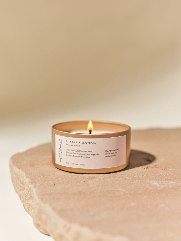 Our Bold + Beautiful affirmation candle features a blend of rose, amber, and oud in a travel tin