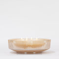 The Votivo Gilded Pear Holiday Multi-Wick Candle, set in a beige ribbed glass bowl with soy blend wax and multiple lit wicks, casts a warm holiday glow against a plain white background.