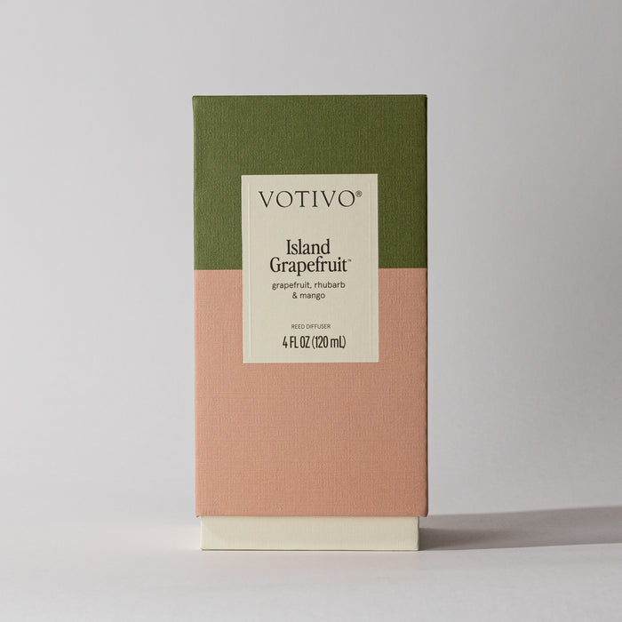 A Votivo Island Grapefruit Reed Diffuser (4 fl oz/120 ml) with a green and peach color block box and cream label, featuring citrus notes of grapefruit, rhubarb, and mango, stands on a light surface.