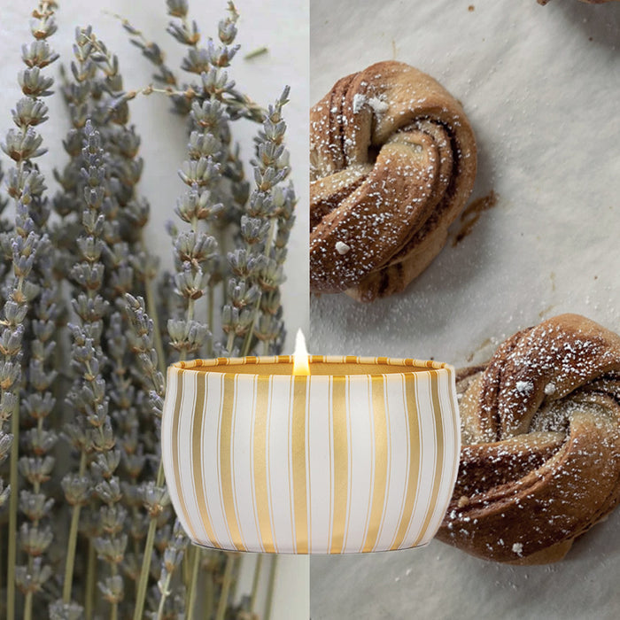 A Votivo Joie De Noel Holiday Tin Candle with a striped design burns beside dried lavender stems and powdered sugar-dusted pastries, filling the space with its delightful soy blend wax aroma.