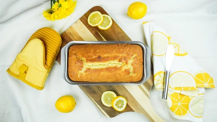 Top view of Loaf Pan with Tab Handles showing loaf and tab handles on wooden cutting board with lemons and yellow oven mitt