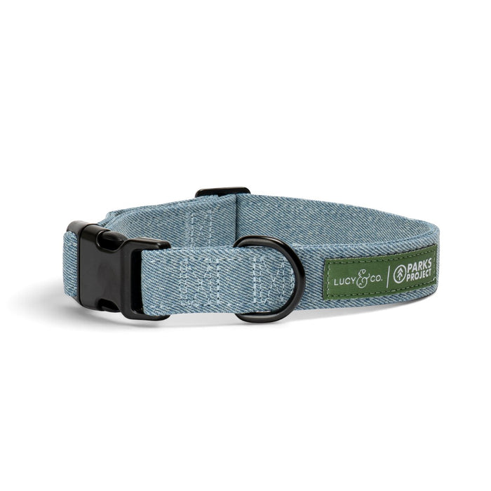 Lucy & Co. x Parks Project dog collar in blue denim-look webbing with black hardware and a green brand patch.