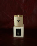 A lit LES Collection Mood candle in a glass jar sits on a white box labeled "LES Collection Mood" against a dark red background.