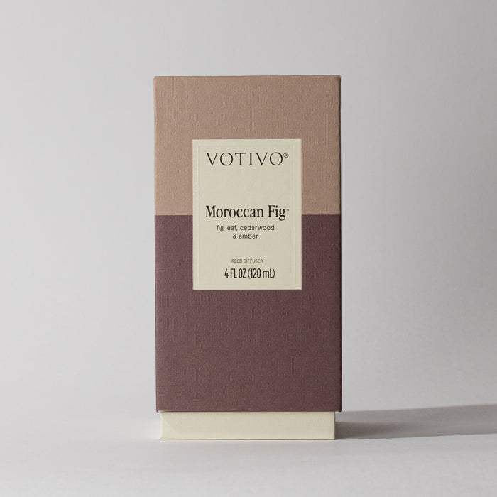 The Votivo Moroccan Fig Reed Diffuser features a mauve and cream rectangular box with a label listing fig leaf, cedarwood, and amber. Enjoy continuous fragrance from 4 fl. oz. (120 mL) of this elegant blend.