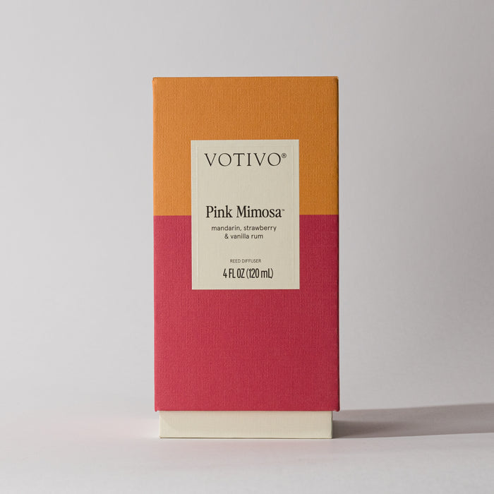 The Votivo Pink Mimosa Reed Diffuser comes in a rectangular box with orange and pink color blocks, offering a fruity mandarin, strawberry, and vanilla rum fragrance in a 4 fl oz (120 ml) size.