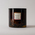 A Votivo Pink Mimosa Tortoise Candle in a dark, mottled glass jar displays the fragrance name and weight (22.7 oz/645 g) on its label, set against a plain light background.