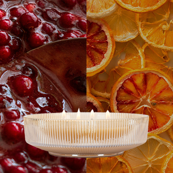 A split image: left, cranberries in sauce; right, dried orange slices. Centered in front is a ribbed glass Votivo Red Currant Holiday Multi-Wick Candle with a soy blend and red currant fragrance.