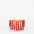 The Votivo Red Currant Holiday Tin Candle features a soy blend wax in a small, round tin with vertical red and gold stripes, displayed against a plain white background.