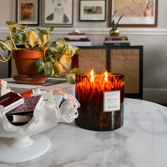 Votive candle on a marble surface with decorative items and framed art in the background
