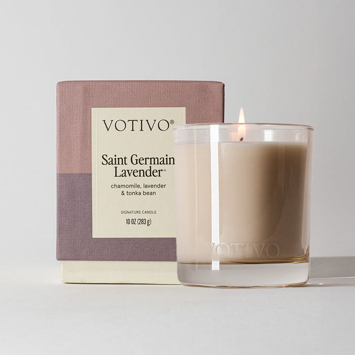 A Votivo Saint Germain Lavender 10 oz. Signature Candle in a clear glass holder is shown with its box—this premium soy blend candle features soothing lavender, chamomile, and tonka bean notes.