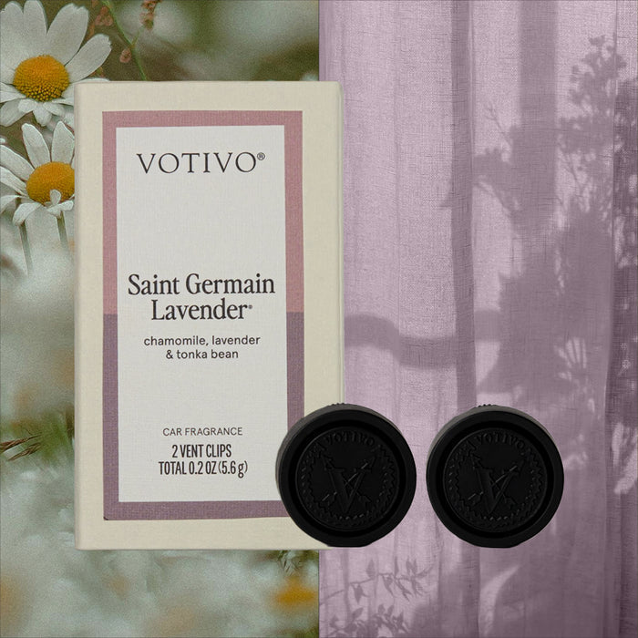 The Votivo Saint Germain Lavender Car Fragrance (2 Pack) is displayed with two black vent clips and notes of chamomile, lavender, and tonka bean. Chamomile flowers and a sheer lavender curtain can be seen in the background.