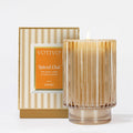 The Votivo Spiced Chai Holiday Candle features chai spices, vanilla, and creamy pumpkin in a soy blend wax. Its ribbed glass jar and gold-striped box add a cozy seasonal glow to any room.