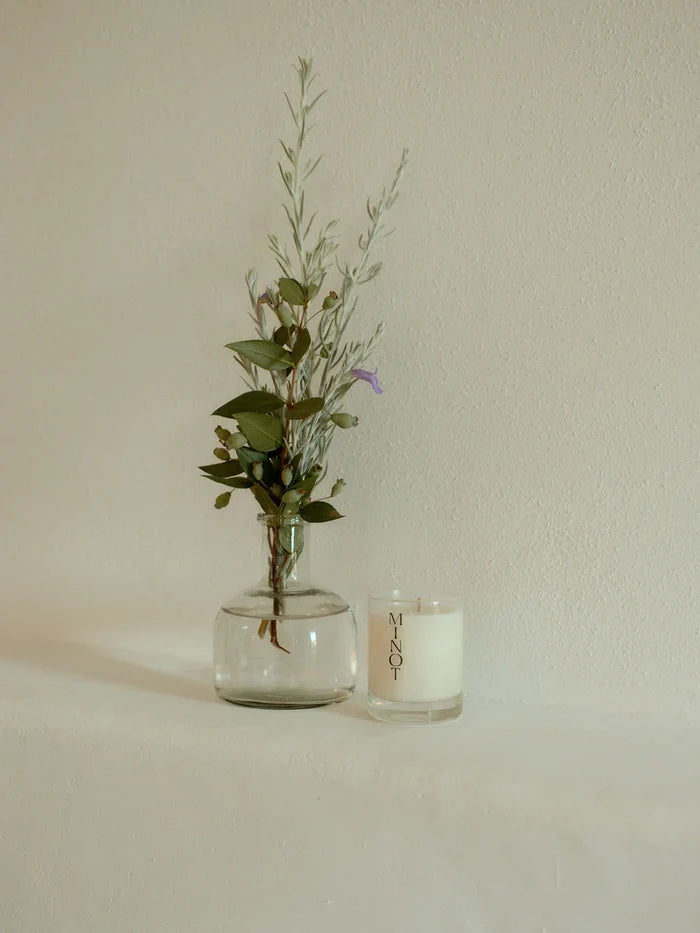 The minimalist Summit Mini candle sits next to a small bouquet of soft greenery and purple flowers