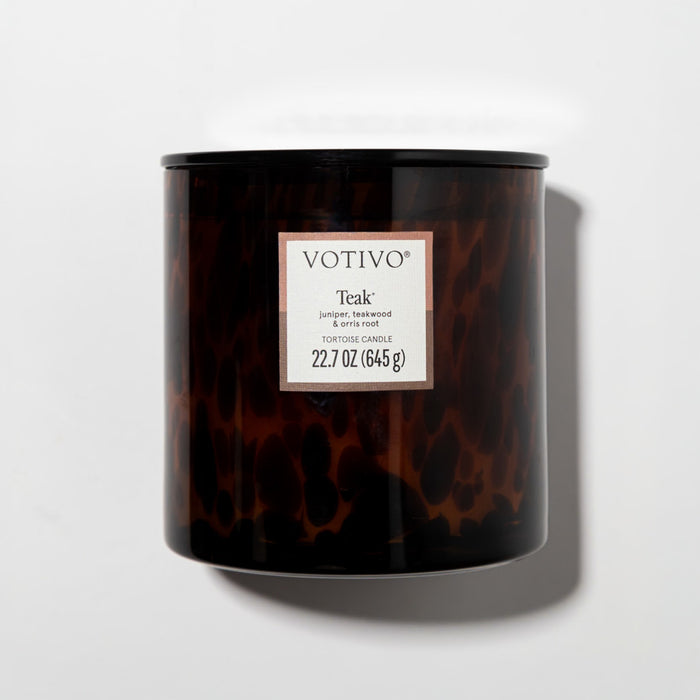 The Votivo Teak Tortoise Candle, a 22.7 oz soy blend candle, features a dark tortoiseshell jar and a teak scent with notes of juniper and orris root, shown on a white background.