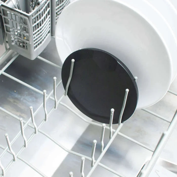 Angled view of Slate Round tool rest nestled between lower-rack dishwasher tines beside a white plate