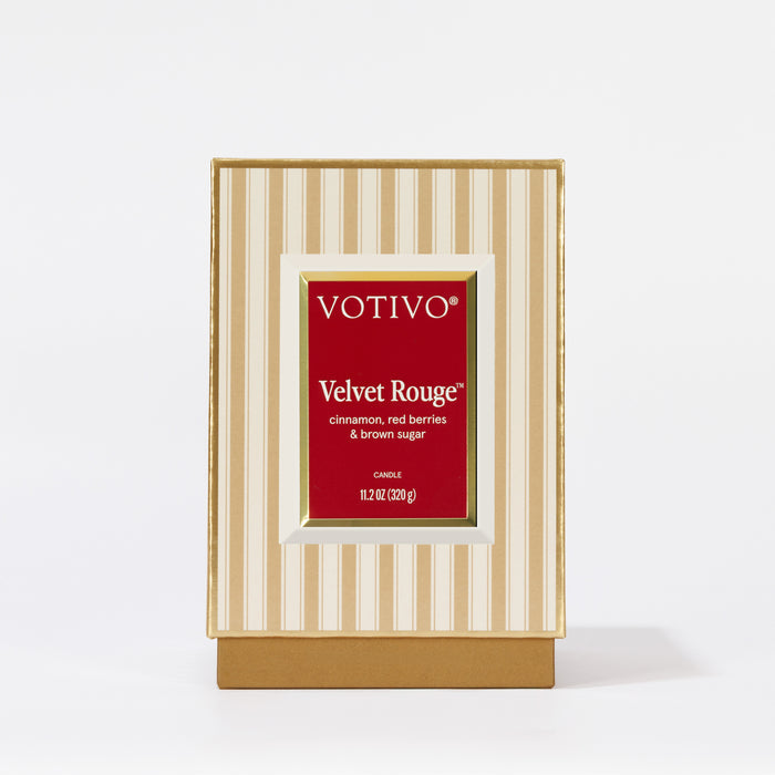 A Votivo Velvet Rouge Holiday Candle, 11.2 oz (320 g), in a gold and cream striped box with a red label featuring "Velvet Rouge," cinnamon, red berries & brown sugar; made from premium soy blend wax.