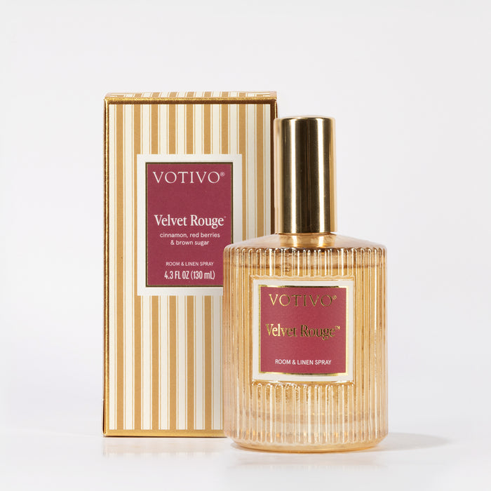 A Votivo Velvet Rouge Room & Linen Spray with a gold cap is shown next to its matching striped gold-and-white box. Both display the Velvet Rouge scent notes: cinnamon, red berries, and brown sugar.