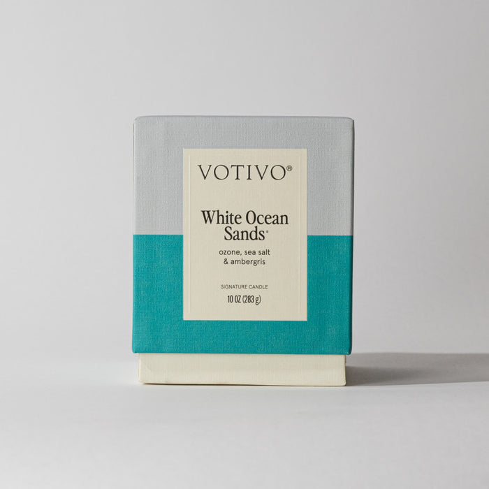 The Votivo White Ocean Sands 10 oz. Signature Candle features a minimalist gray, teal, and cream design with the scent of ozone, sea salt & ambergris. Made with premium soy blend wax.