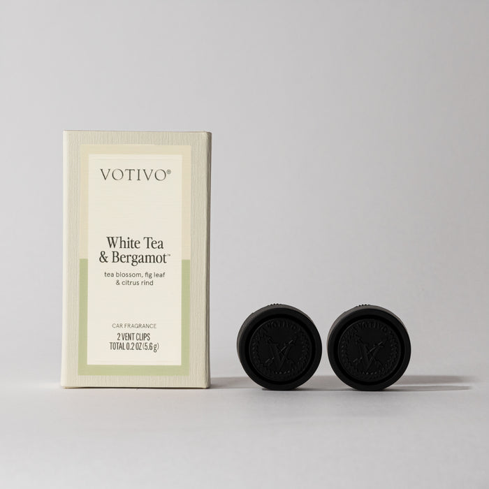 Votivo White Tea & Bergamot Car Fragrance (2 Pack) stands upright by two round black vent clips with embossed logos, delivering paraben-free scent on-the-go against a simple light background.