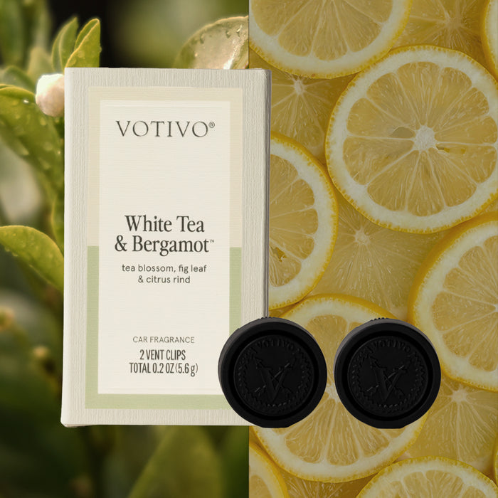Votivo White Tea & Bergamot Car Fragrance (2 Pack) vent clips, paraben free, are shown in packaging with fresh green leaves and overlapping lemon slices in the background.